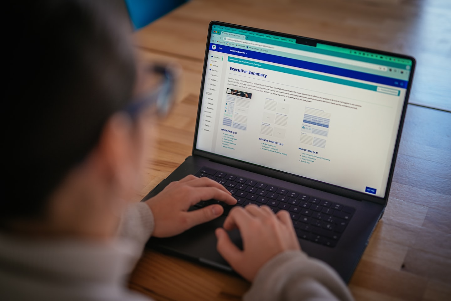 Professional typing an executive summary on a laptop computer.